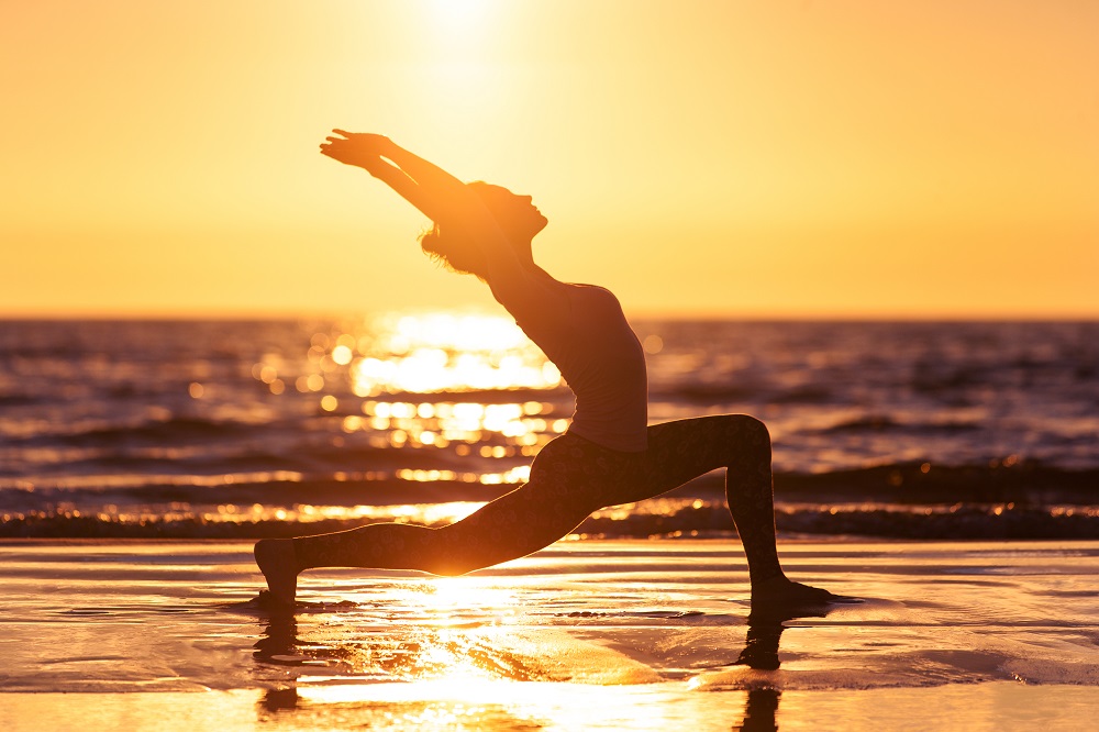 Donna pratica Yoga sulla spiaggia e aumenta l'autostima